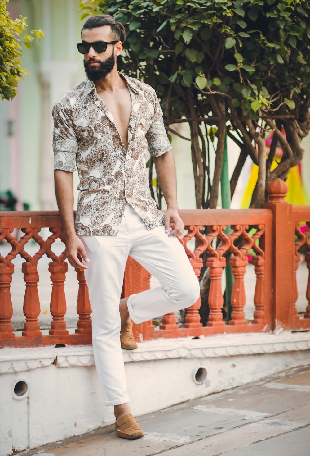 a man with a beard wearing a floral shirt and white pants