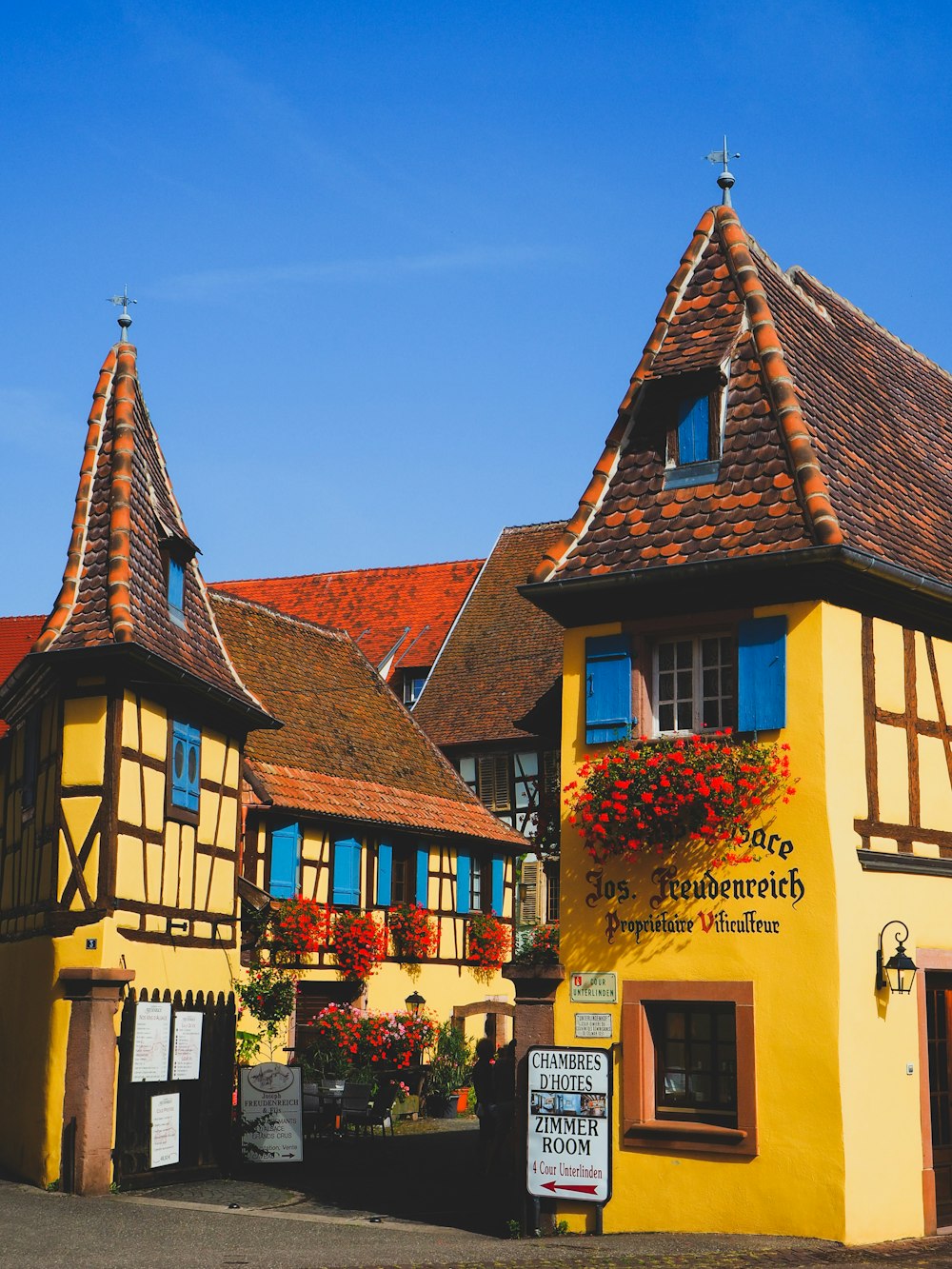 a yellow and brown building with flowers on the windows