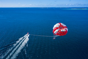 a person is parasailing over the ocean with a boat