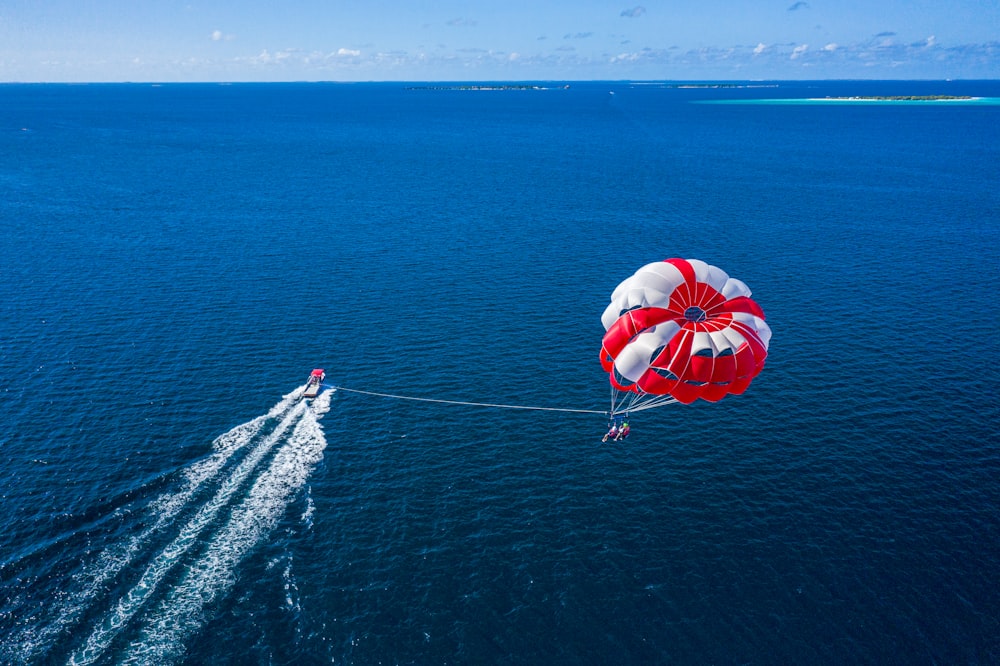 Une personne fait du parachute ascensionnel au-dessus de l’océan avec un bateau
