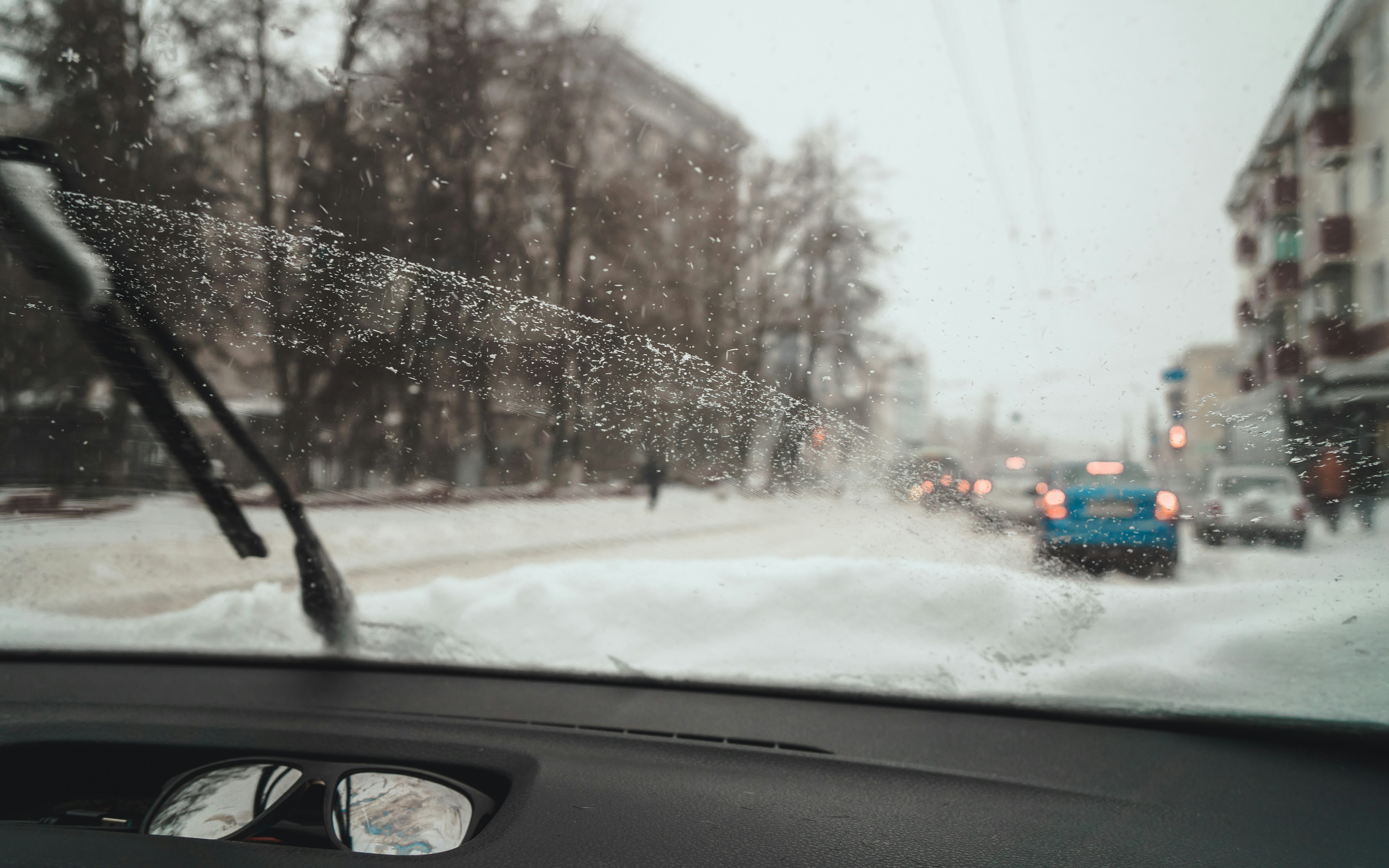 a view of a snowy street from inside a car