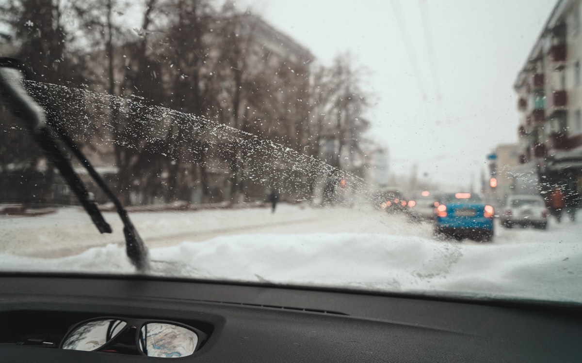 View from inside car showing snowy street through windshield - winter visibility importance