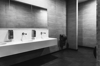 a black and white photo of a public bathroom