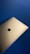 A sleek, silver laptop with a prominent black apple logo on its lid is positioned against a solid blue background. The contrast between the metallic finish of the laptop and the deep blue backdrop creates a striking composition.