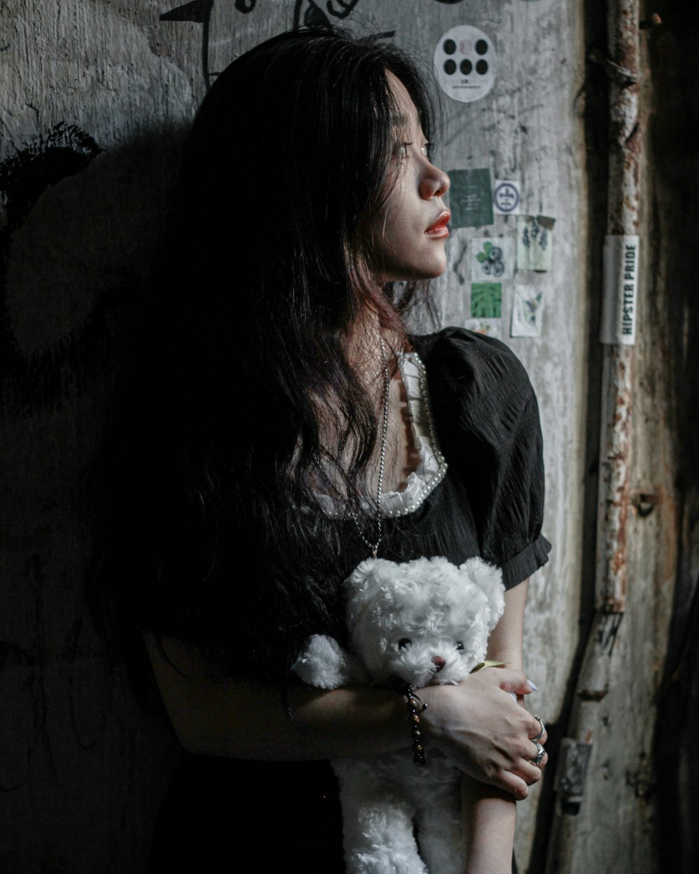 a woman in a black dress holding a white teddy bear