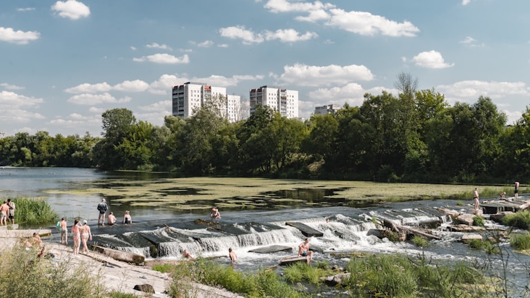 A serene riverside view with families enjoying nature.