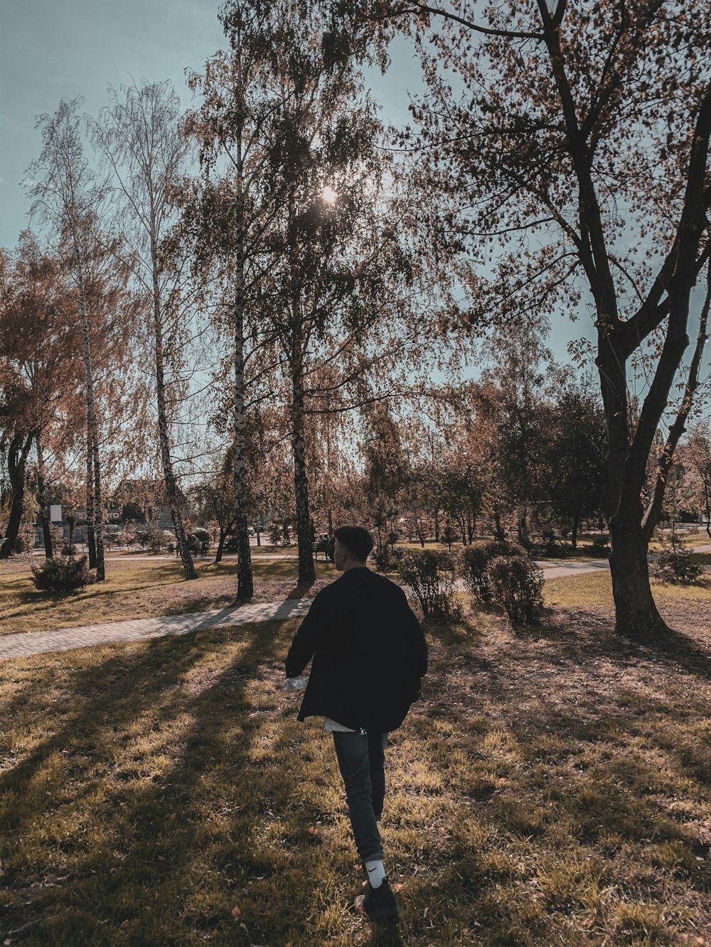 a man walking through a park next to a tree
