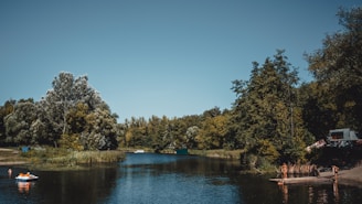 A serene lakeside scene with people kayaking under a clear blue sky.