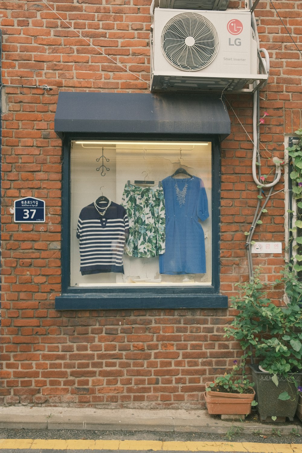 파란색과 흰색 셔츠를 전시하는 창문이 있는 벽돌 건물