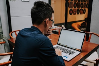 a man sitting at a table using a laptop computer