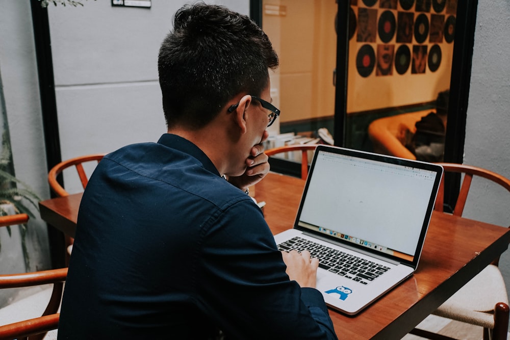 a man sitting at a table using a laptop computer