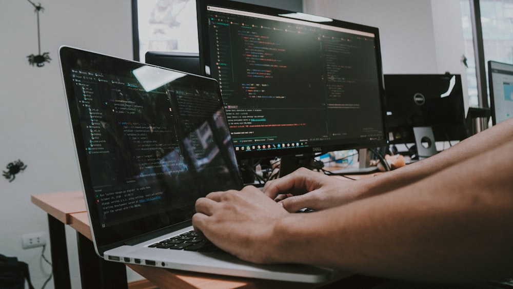 Una persona escribiendo en una computadora portátil en un escritorio