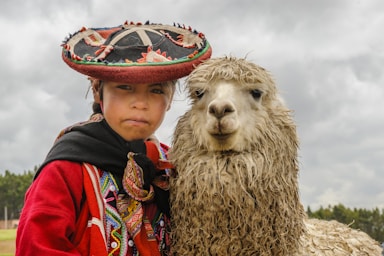 a woman in a sombrero standing next to a llama