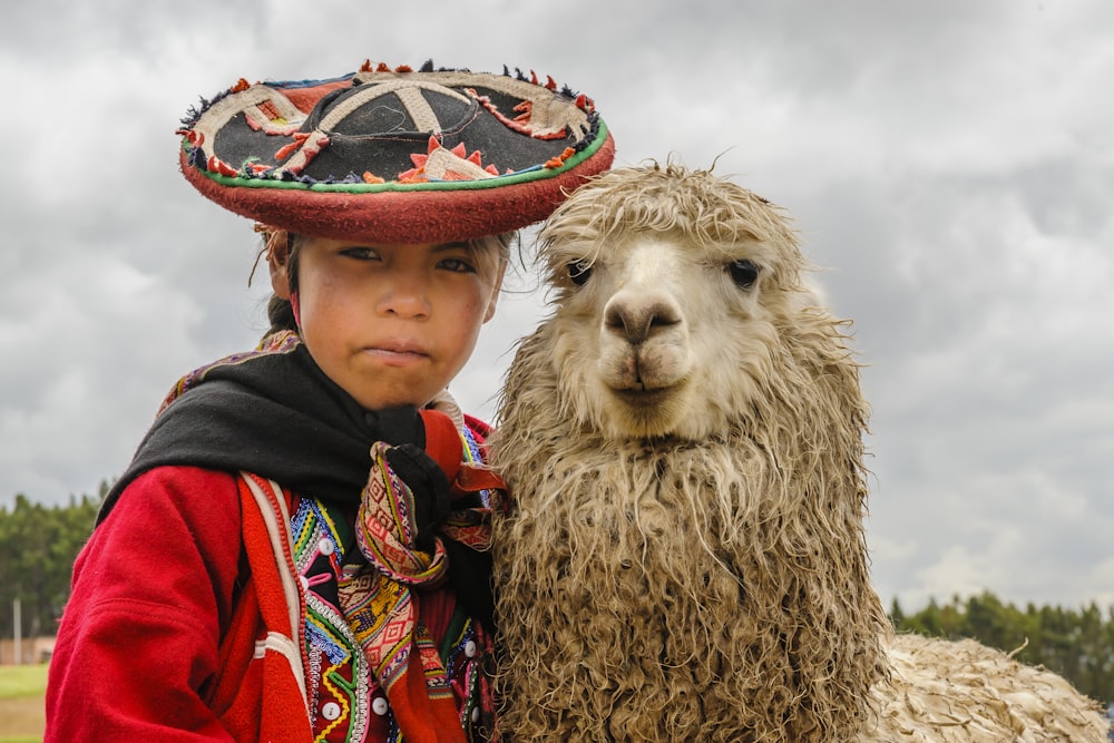 a woman in a sombrero standing next to a llama