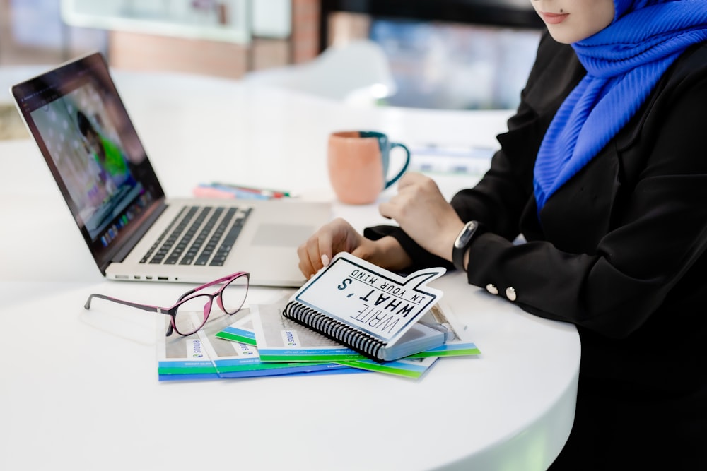 a woman sitting at a table working on a laptop