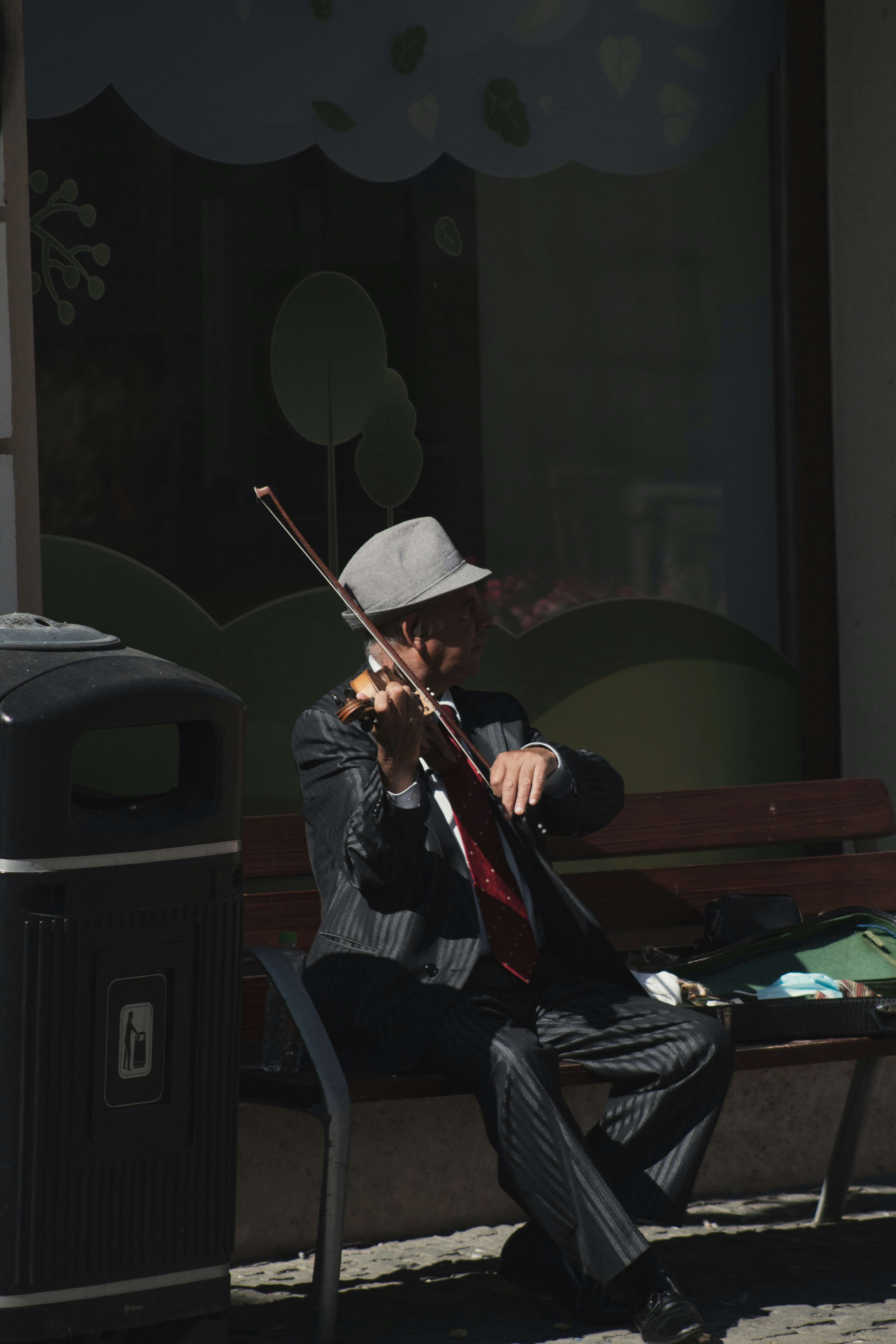 A man sitting on a bench playing a violin photo – Free Man Image on ...