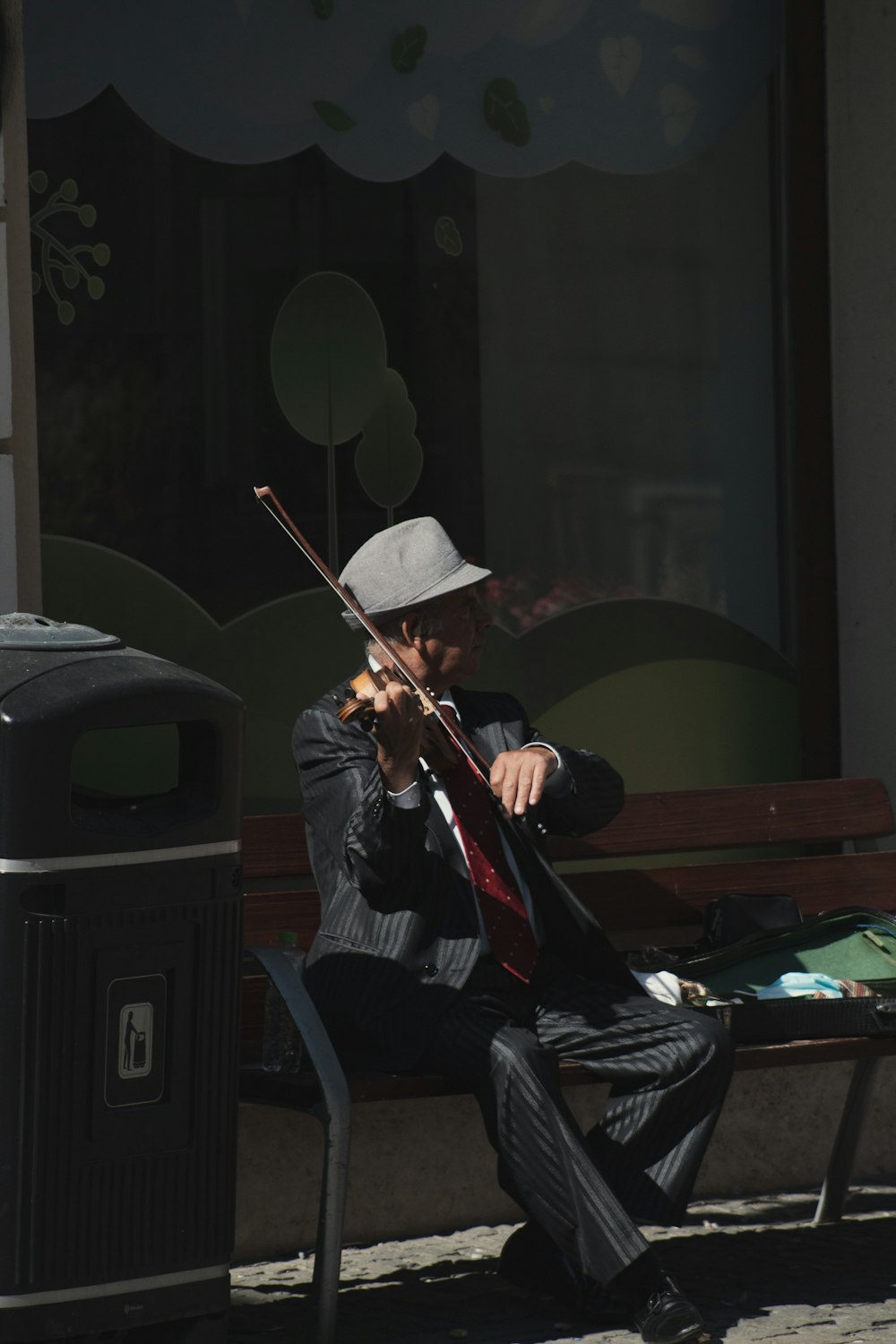 a man sitting on a bench playing a violin