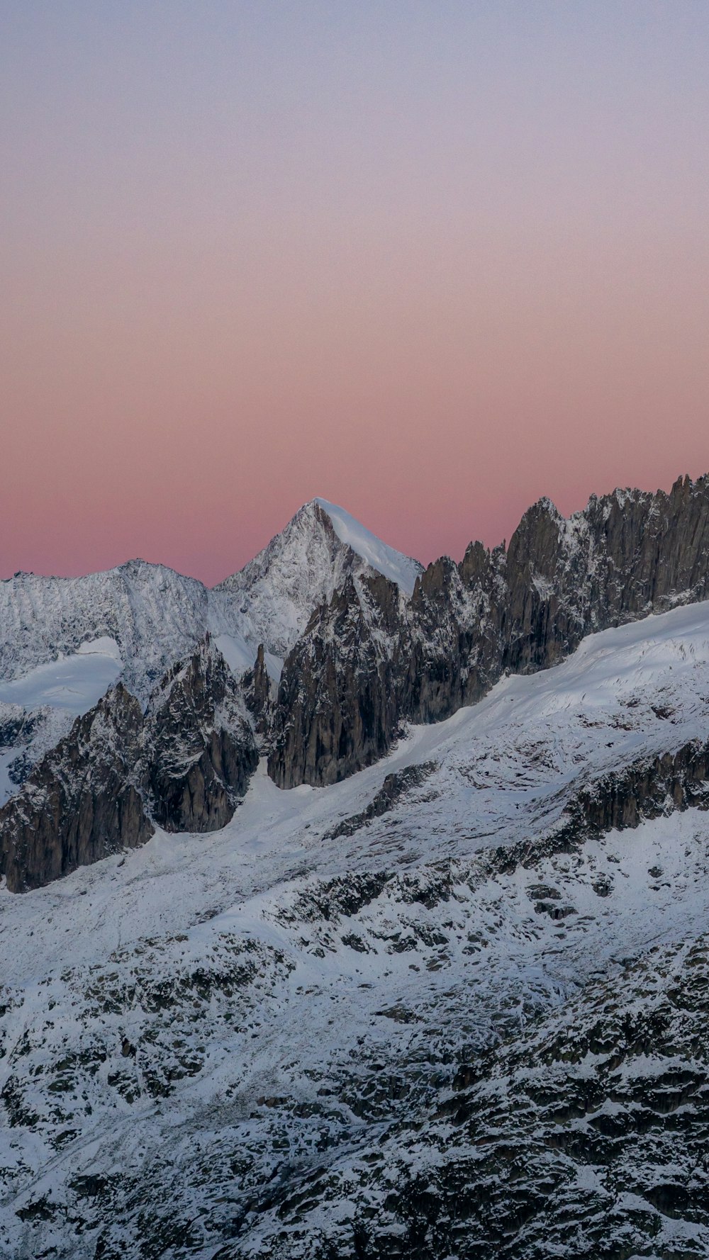 a snow covered mountain with a pink sky in the background