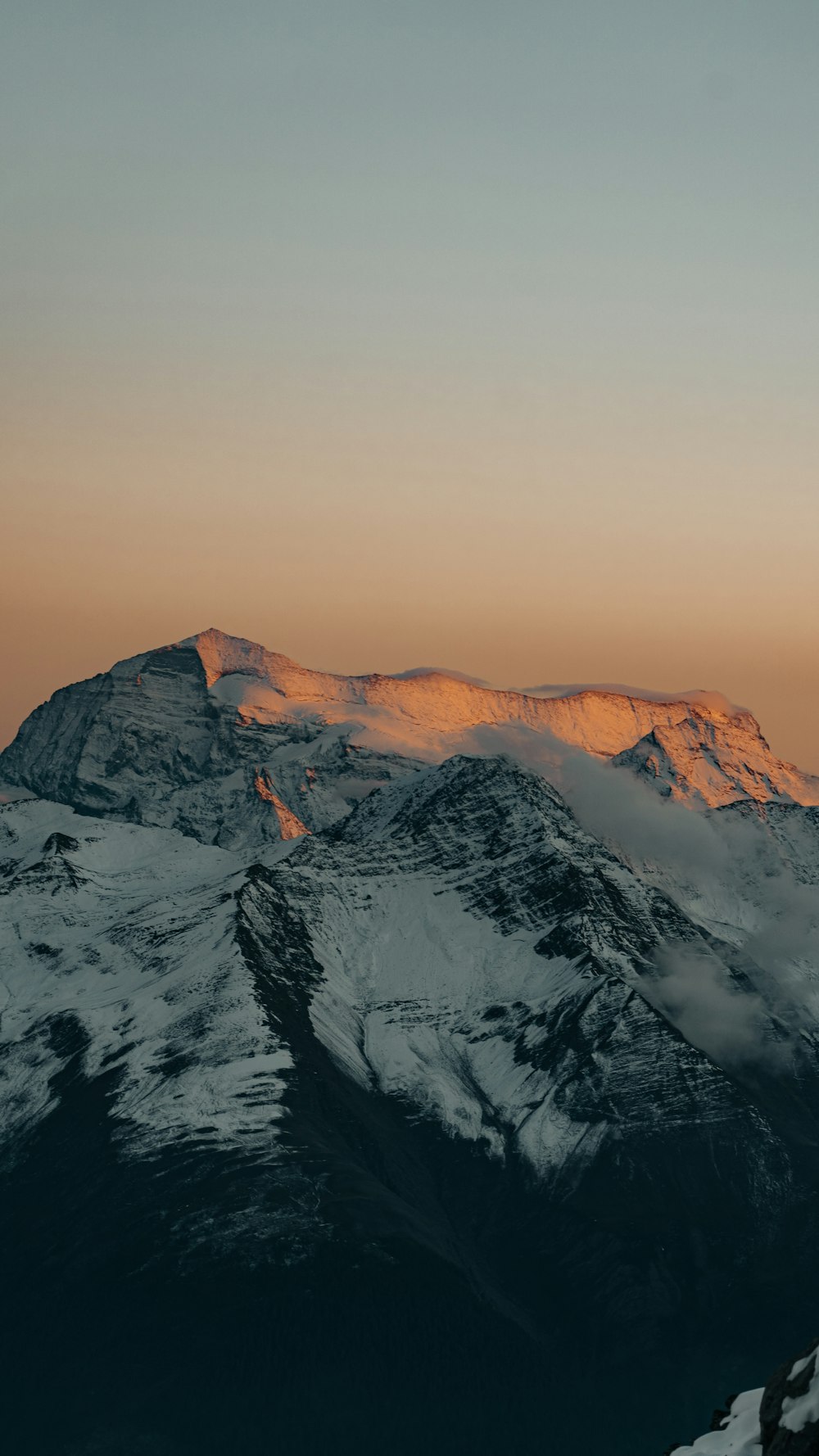 a snow covered mountain with a sunset in the background