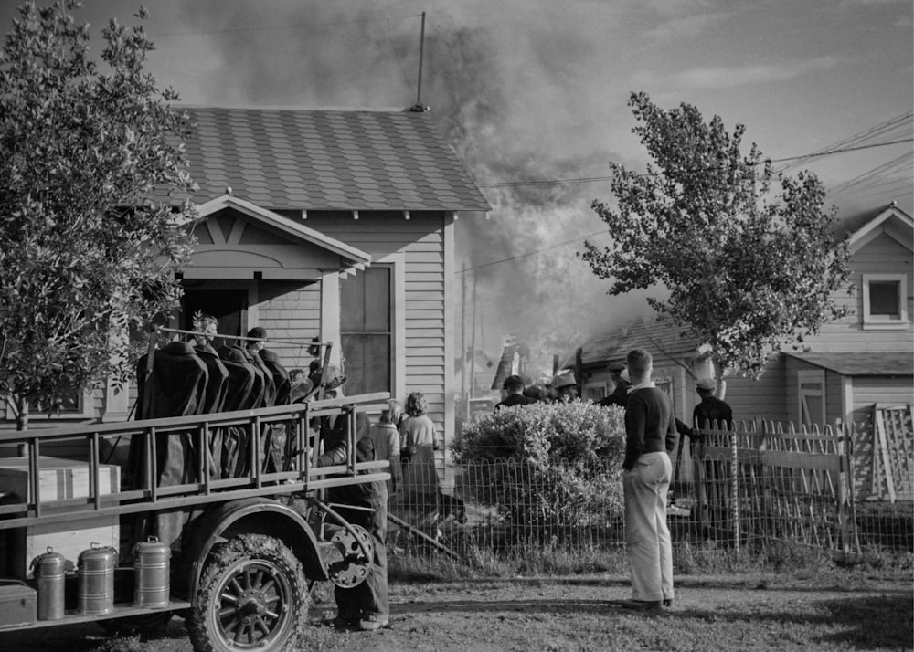 Une photo en noir et blanc d’un homme debout devant un camion de pompiers