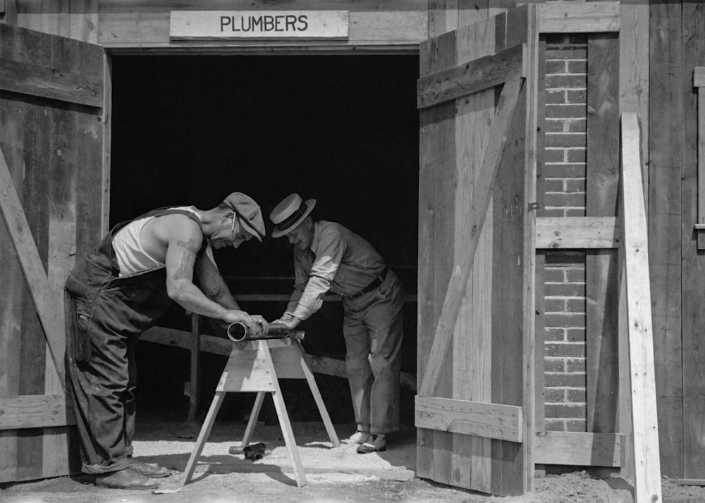 a couple of men working on a wooden structure