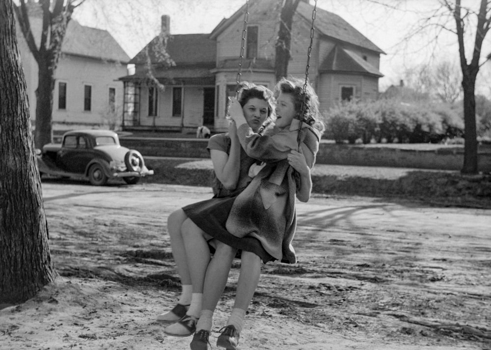 a black and white photo of a woman sitting on a swing