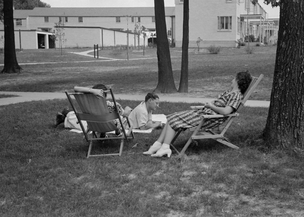 a couple of people sitting in lawn chairs next to a tree