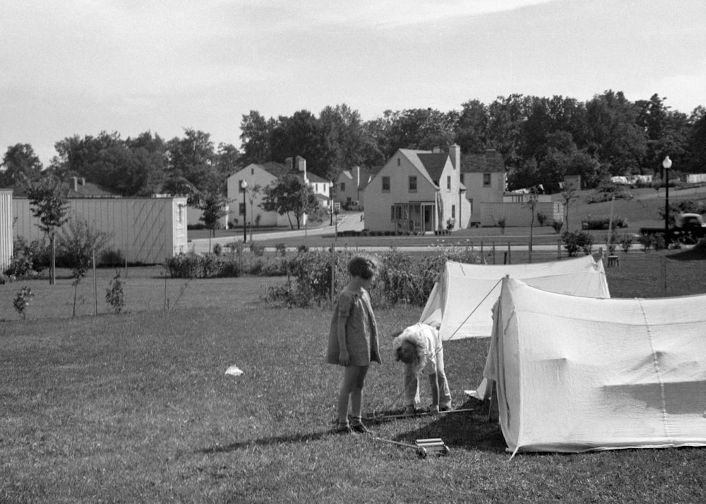 a black and white photo of two people near a tent