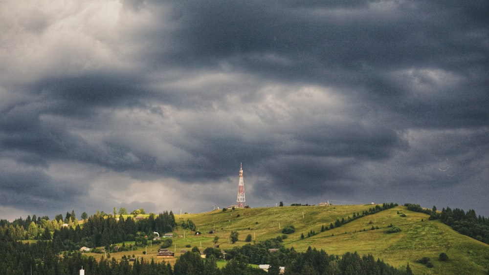 una colina con una torre en la cima bajo un cielo nublado