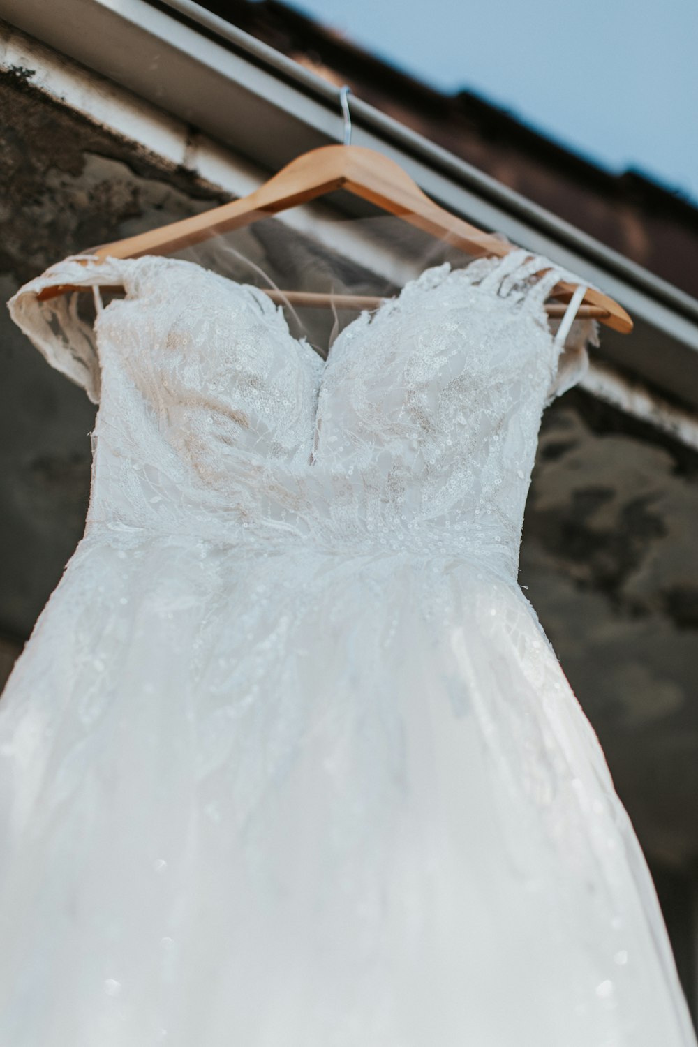 a wedding dress hanging on a wooden hanger