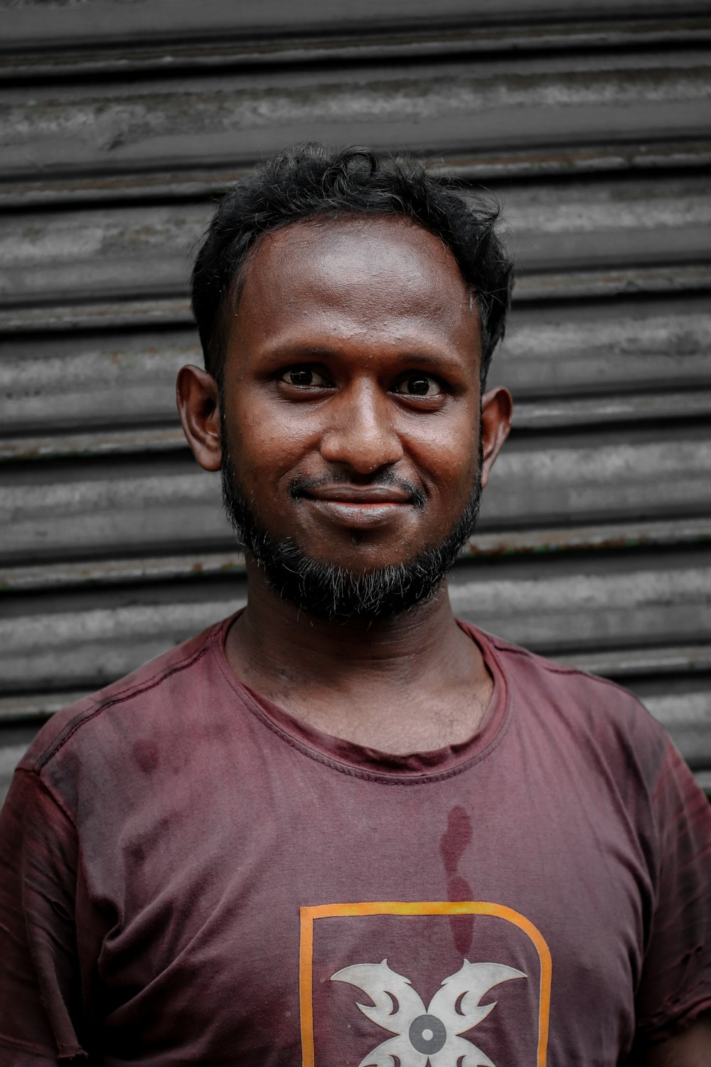 a man with a goatee standing in front of a building