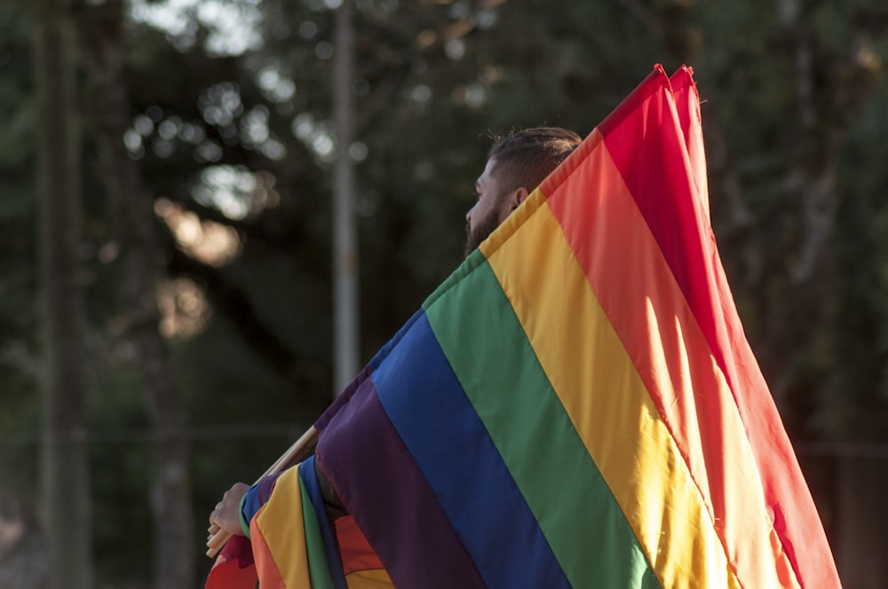 Un hombre sosteniendo una bandera del arco iris en sus manos