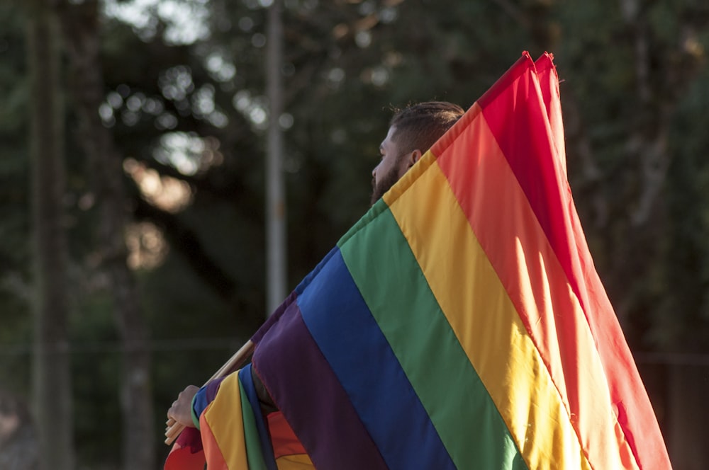 a man holding a rainbow flag in his hands