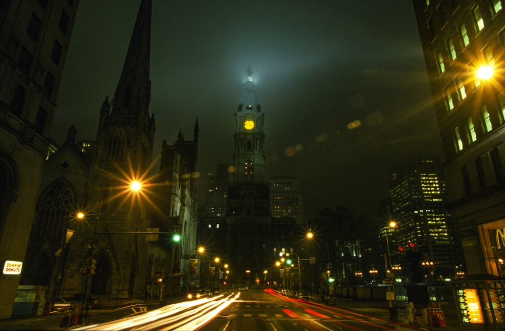 a city street at night with a clock tower in the background