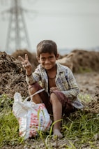 a young boy sitting on the ground with a bag of food