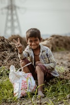 a young boy sitting on the ground with a bag of food