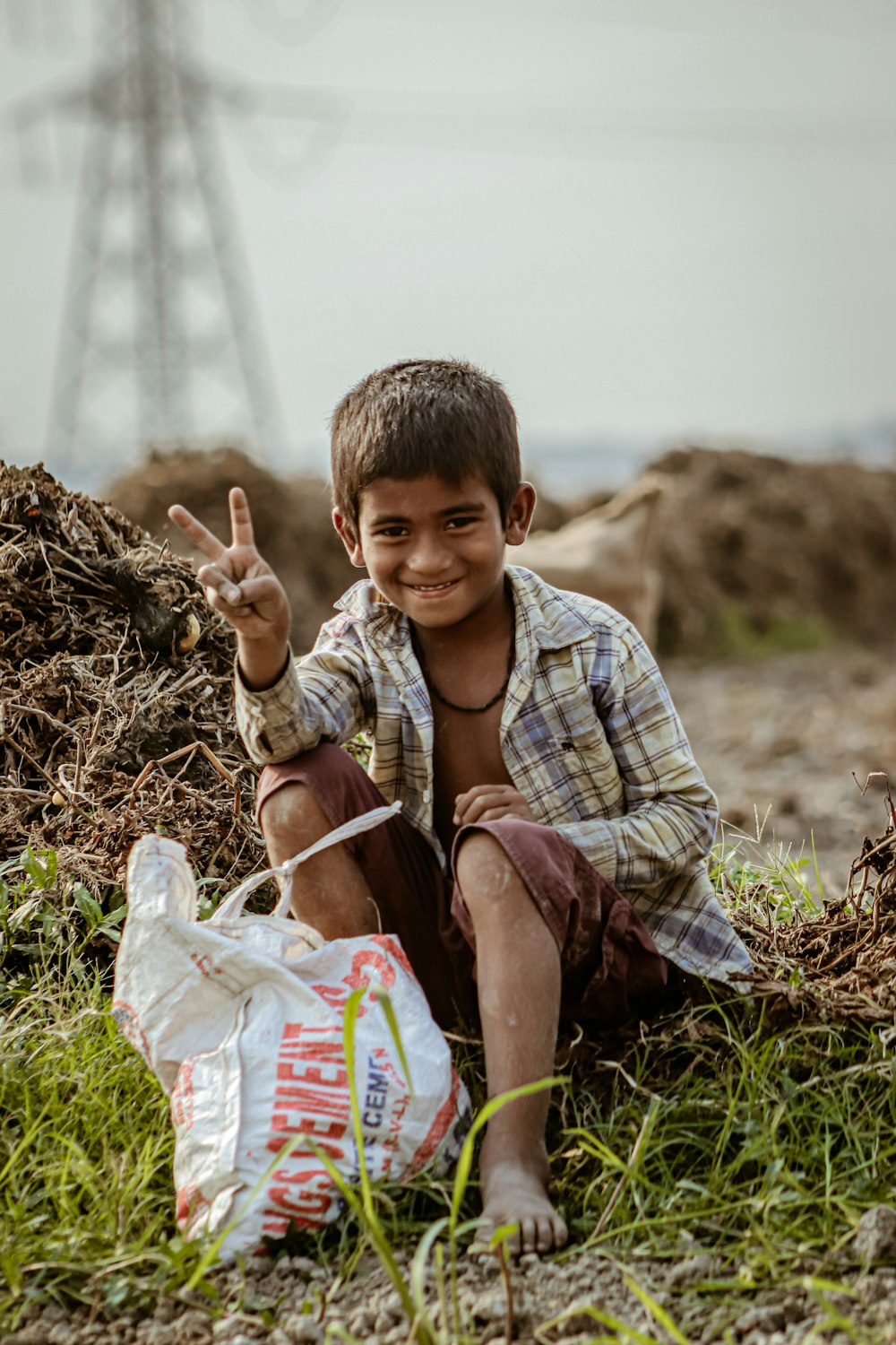 a young boy sitting on the ground with a bag of food