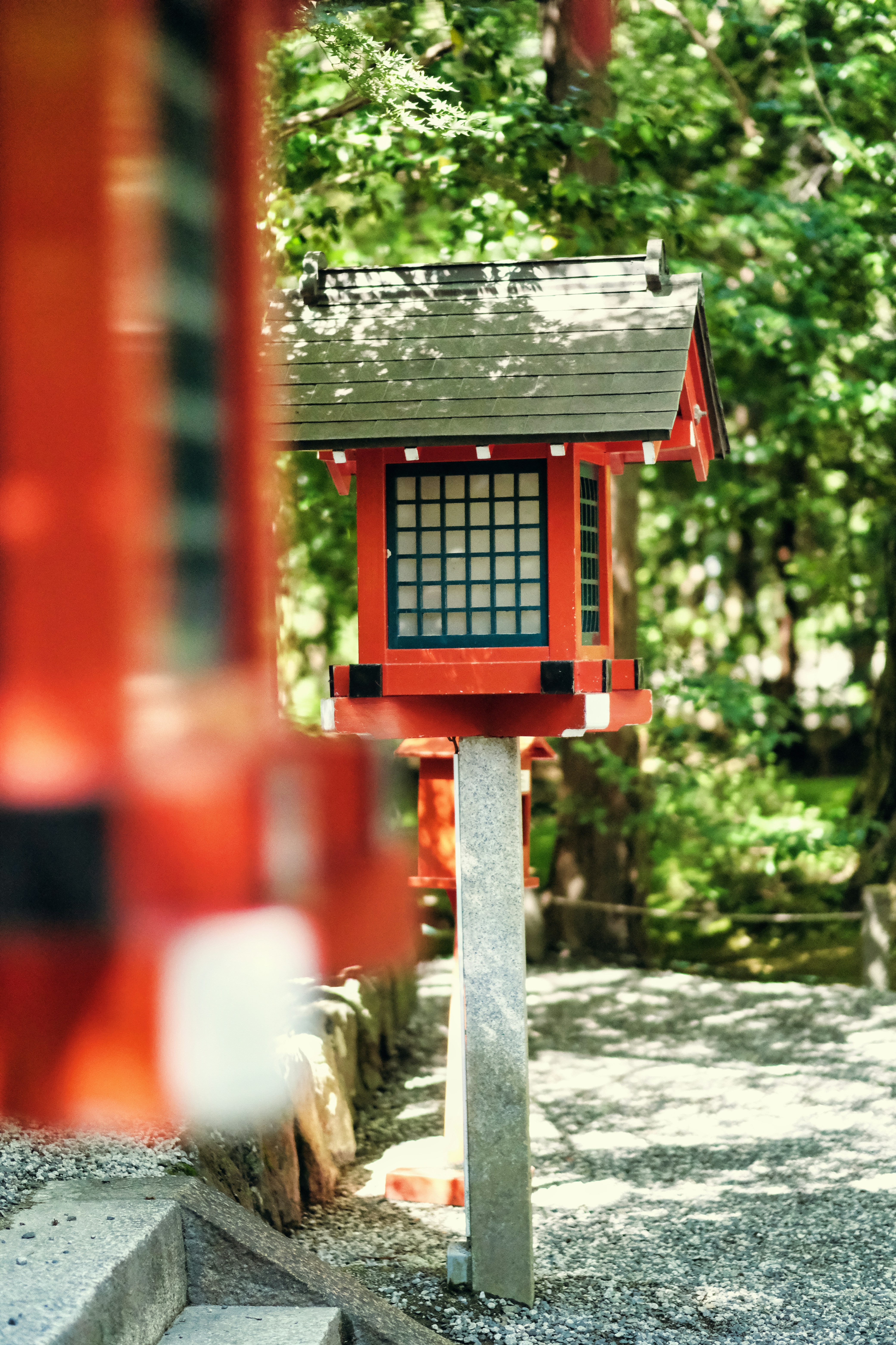 a red bird house sitting on the side of a road