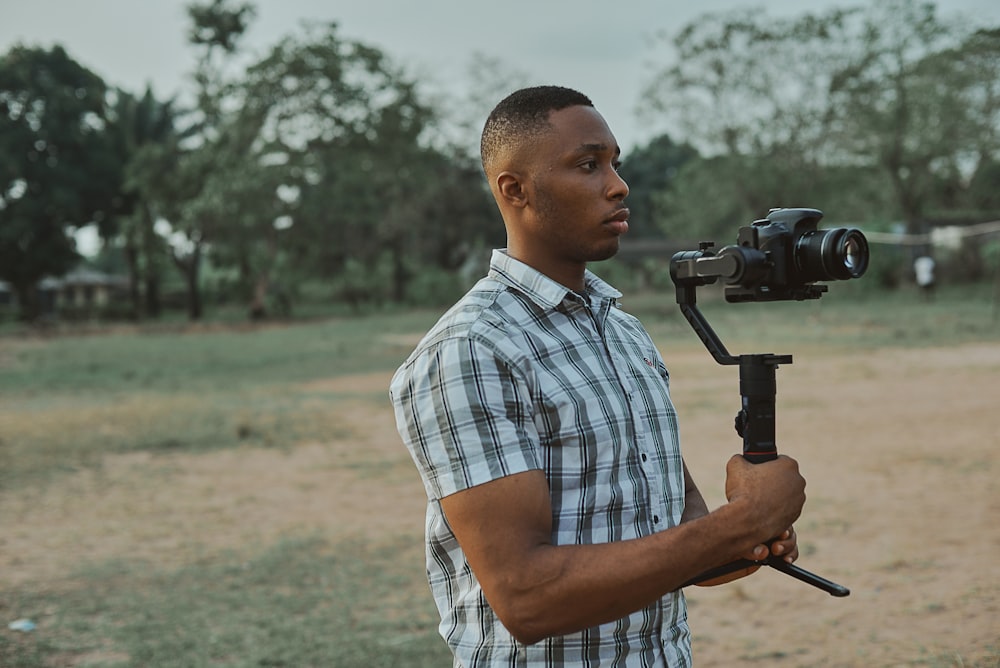 a man holding a video camera in a field