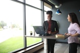 a woman standing at a desk in front of a laptop computer