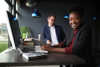 a man and a woman sitting at a desk in front of a computer