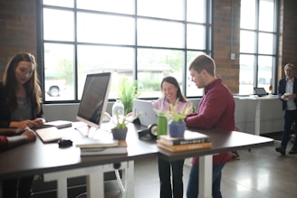 a group of people standing around a table with a laptop