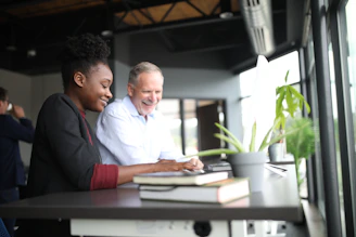 Friendly advisor discussing retirement plans with a smiling couple at a bright desk.