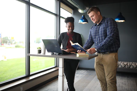 a man standing next to a woman on a laptop