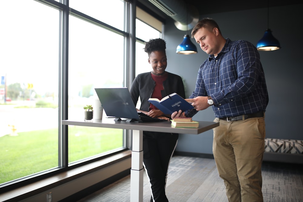 a man and a woman are looking at a book