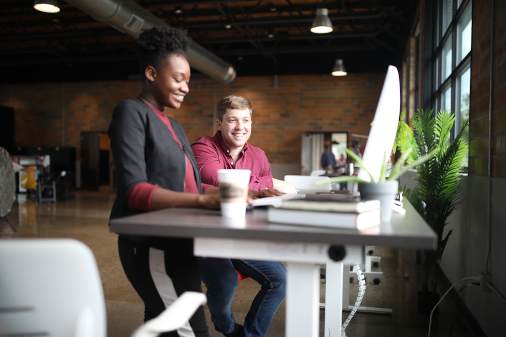 two people sitting at a table with a laptop