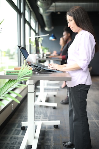 a woman standing at a table using a laptop computer