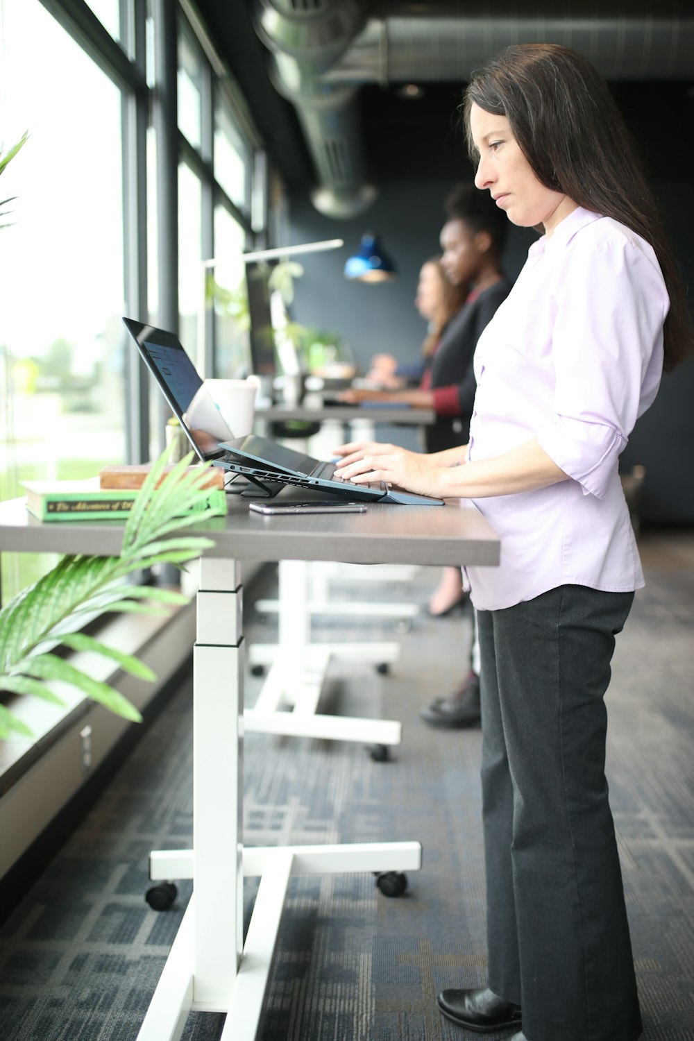 a woman standing at a table using a laptop computer