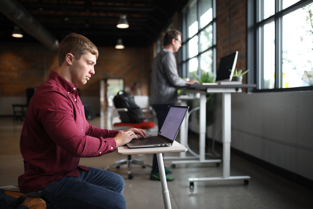 a man sitting at a desk using a laptop computer