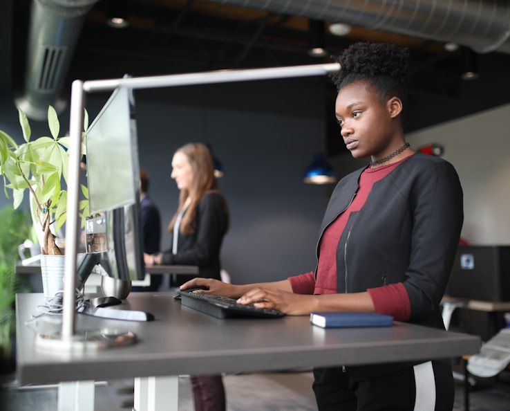 a woman standing at a desk using a computer